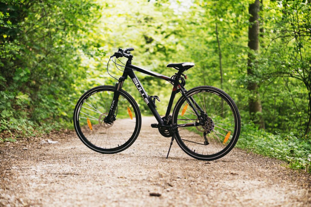 pexels-photo-100582-100582 A mountain bike resting on a forest path surrounded by lush green trees in broad daylight.